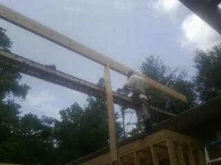 Carpenter setting a ridge beam over a new addition frame — Ice Dam Removal by Roofing Brothers in Prospect Hill