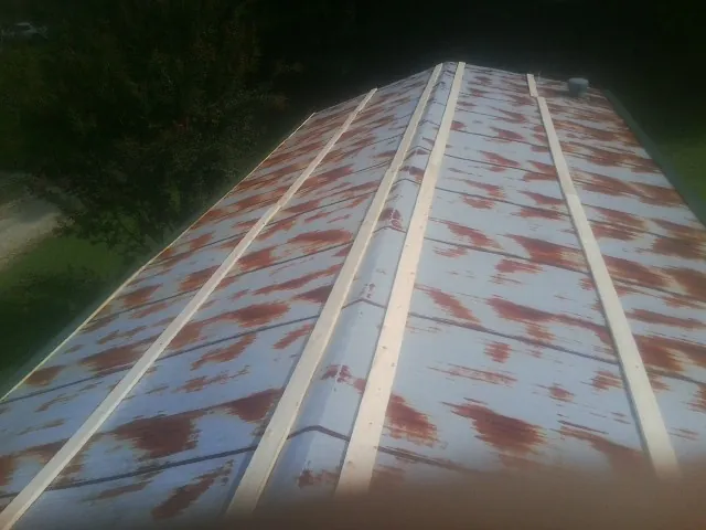 Rusted metal roof panels with new wood purlins before replacement — Storm Damage Roof Repair in Prospect Hill by Roofing Brothers