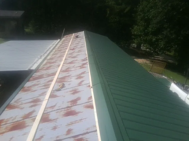 Old rusted panels beside newly installed green metal roofing — Wind Damage Roof Repair by Roofing Brothers in Prospect Hill
