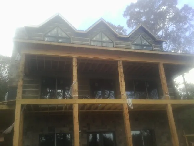 Dormers and porch framing on a large log home under construction — Roof Coating work by our crew in Prospect Hill