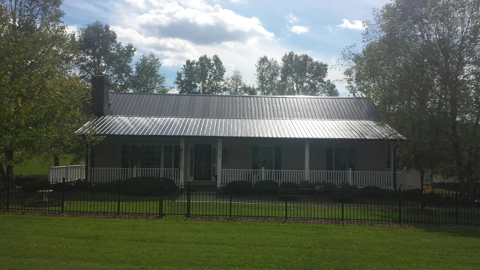 Gray metal roof on a brick ranch with a full width front porch — Gutter Guard Installation work by our crew in Prospect Hill