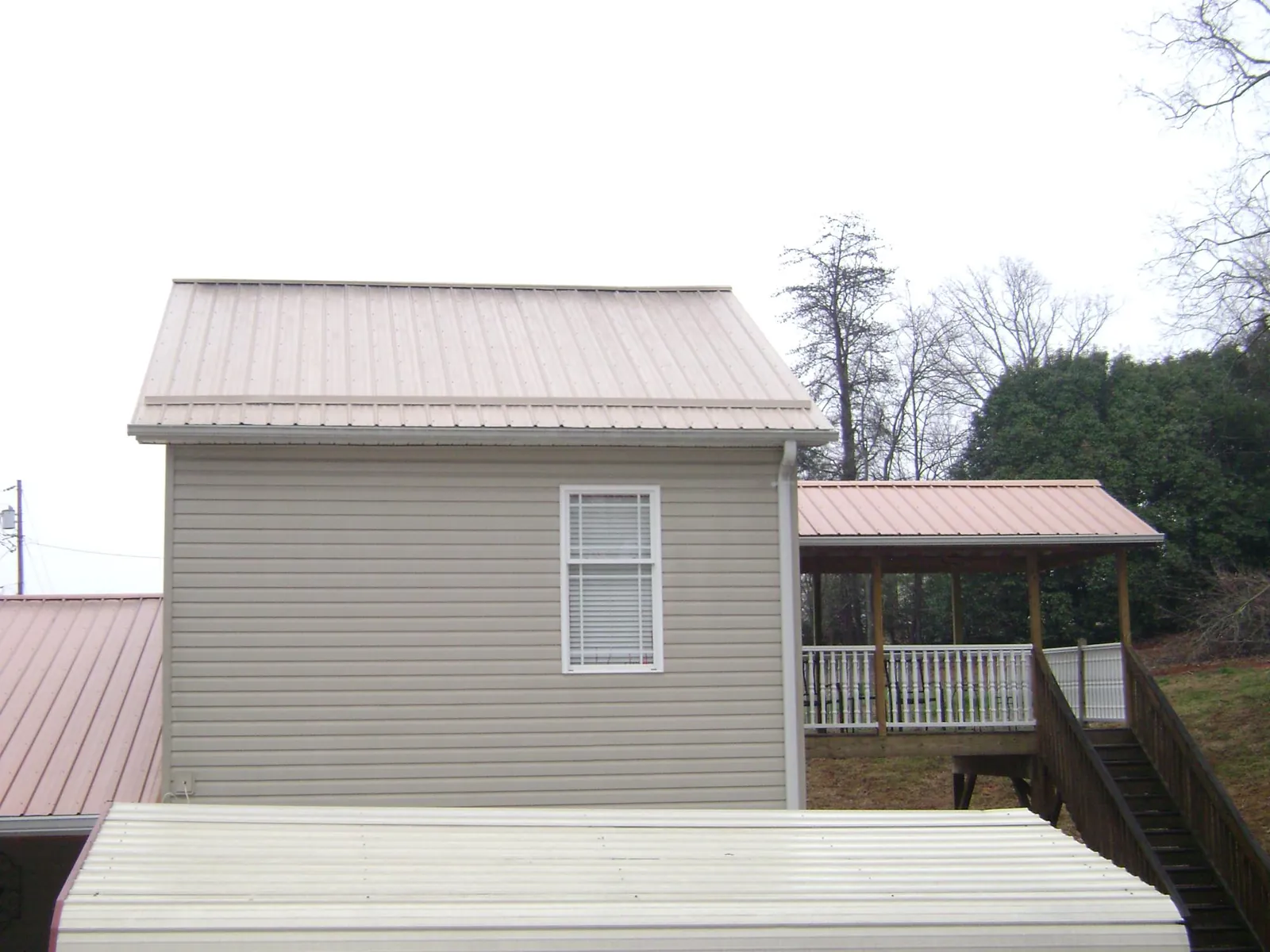 Tan metal roofs on a two story addition and attached porch, from a Roof Replacement job in Prospect Hill