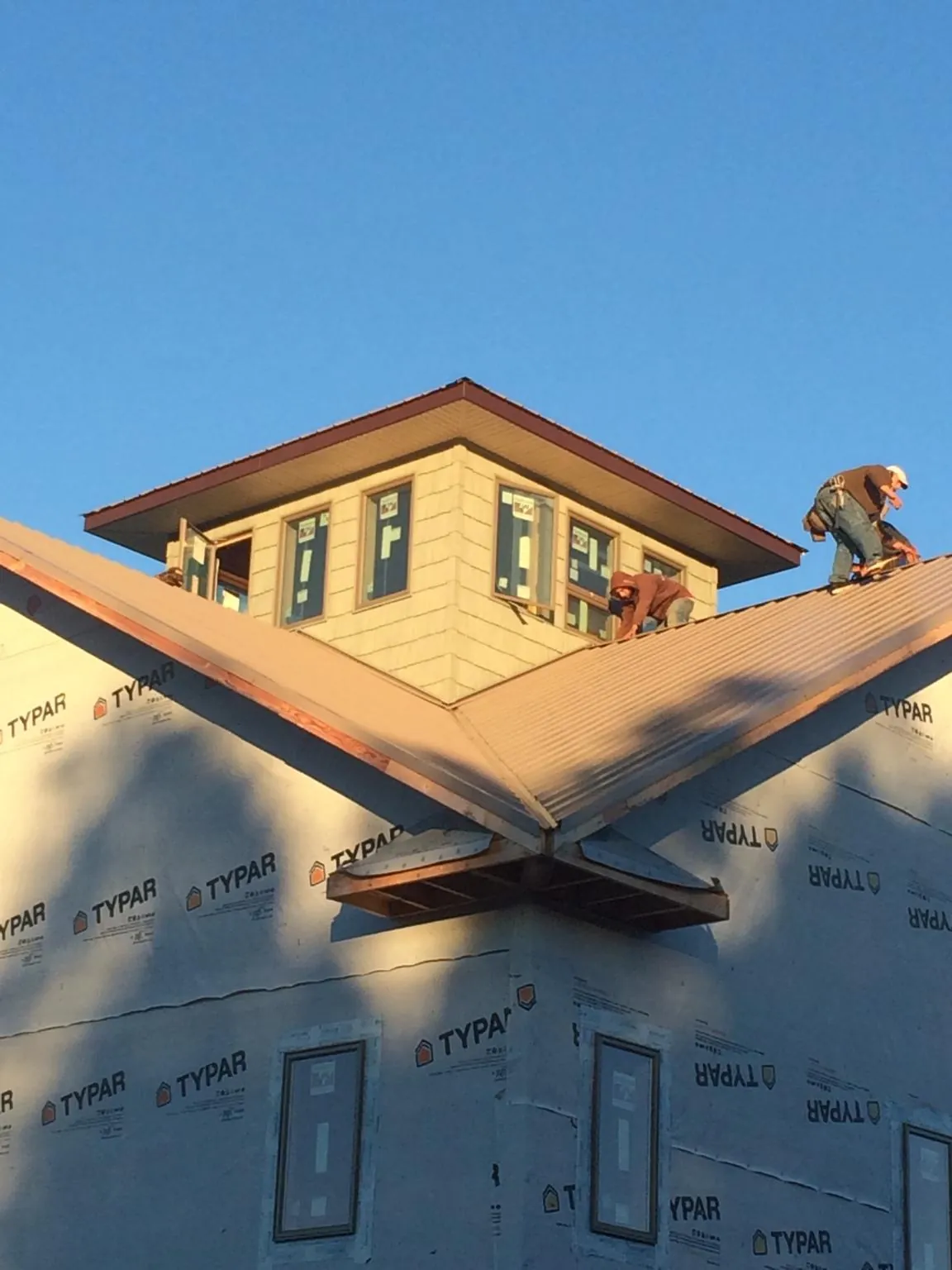 Roofers working around a rooftop cupola on a new metal roof at sunset — Roof Waterproofing in Prospect Hill by Roofing Brothers